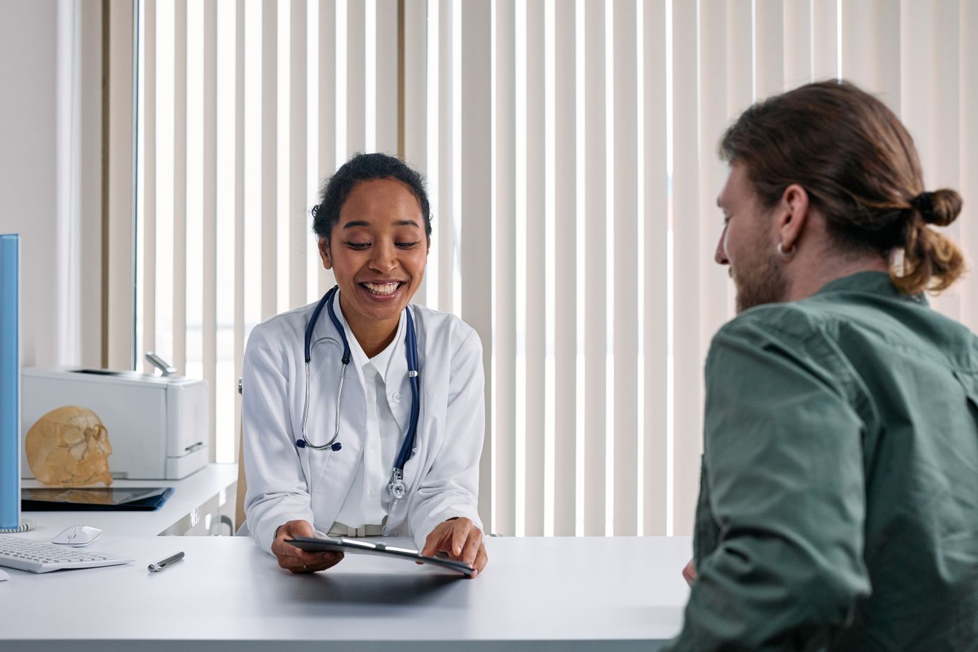 Smiling doctor talking with a patient across her desk