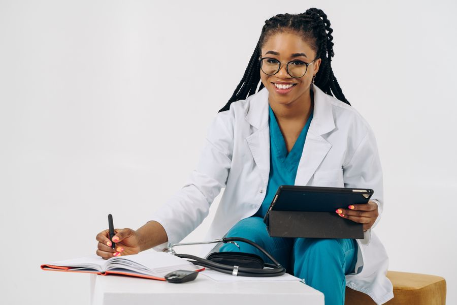 Smiling doctor with a stethoscope using a tablet