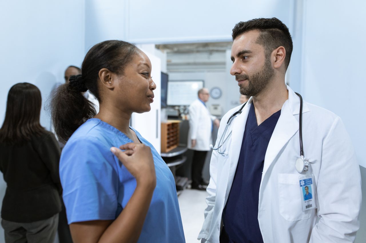 Nurse and doctor discussing patient care in a hospital corridor